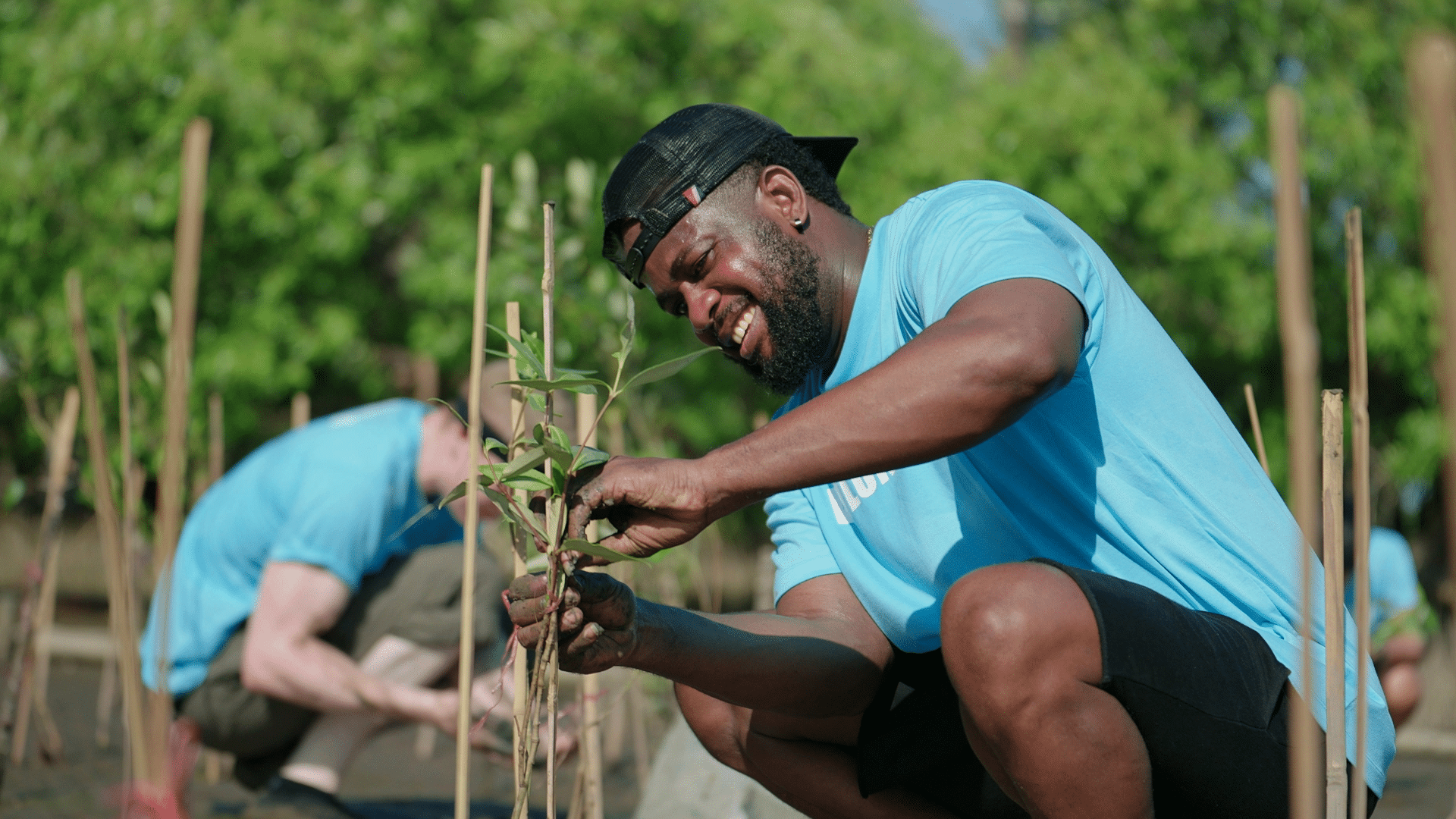 A smiling volunteer planting a young tree sapling during an environmental conservation project