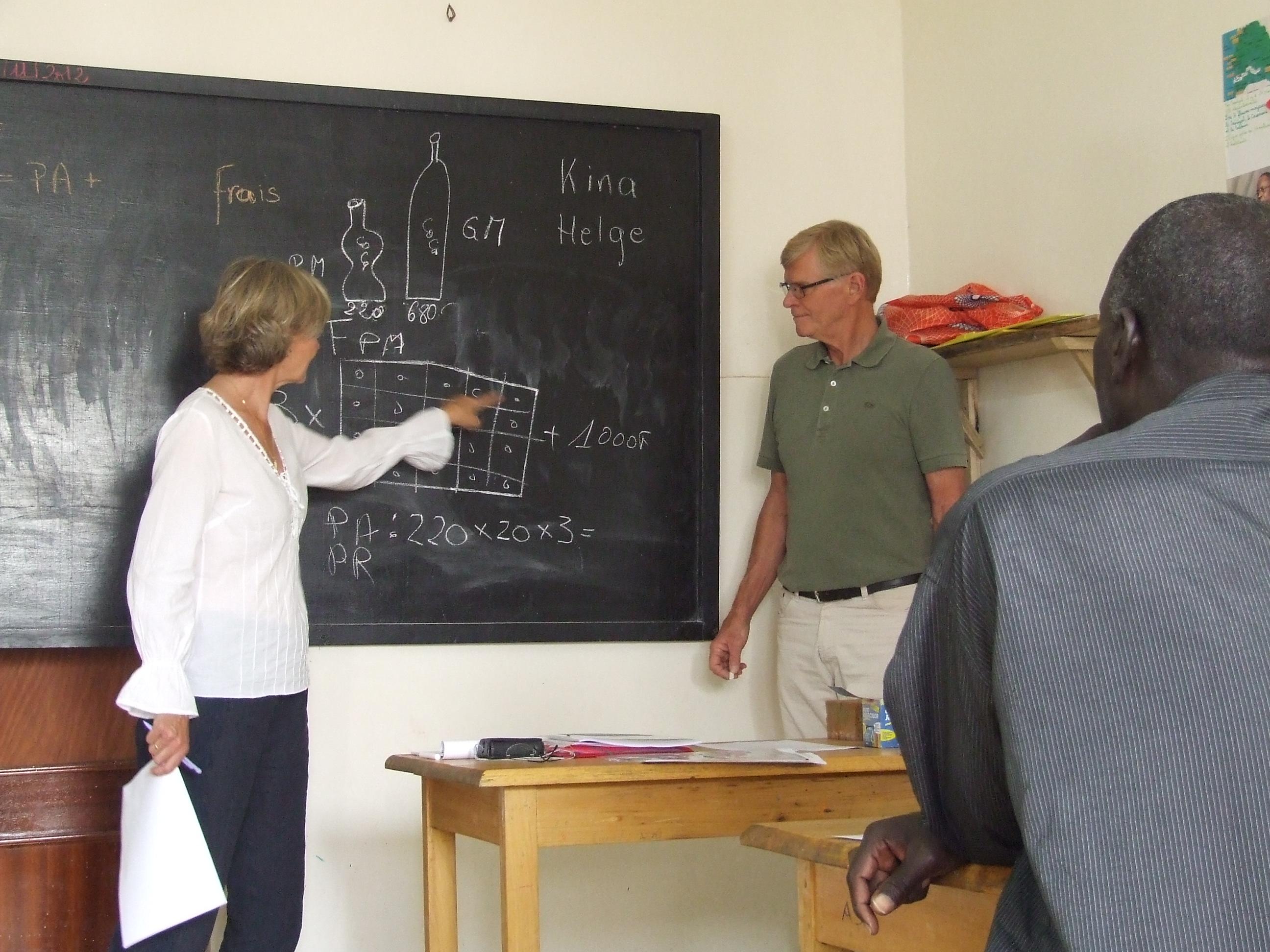 Two older people volunteering in Africa teach a maths class at a Micro-finance Project Students in Africa attend a maths class taught by older adults volunteering abroad on a Projects Abroad Micro-finance Project.