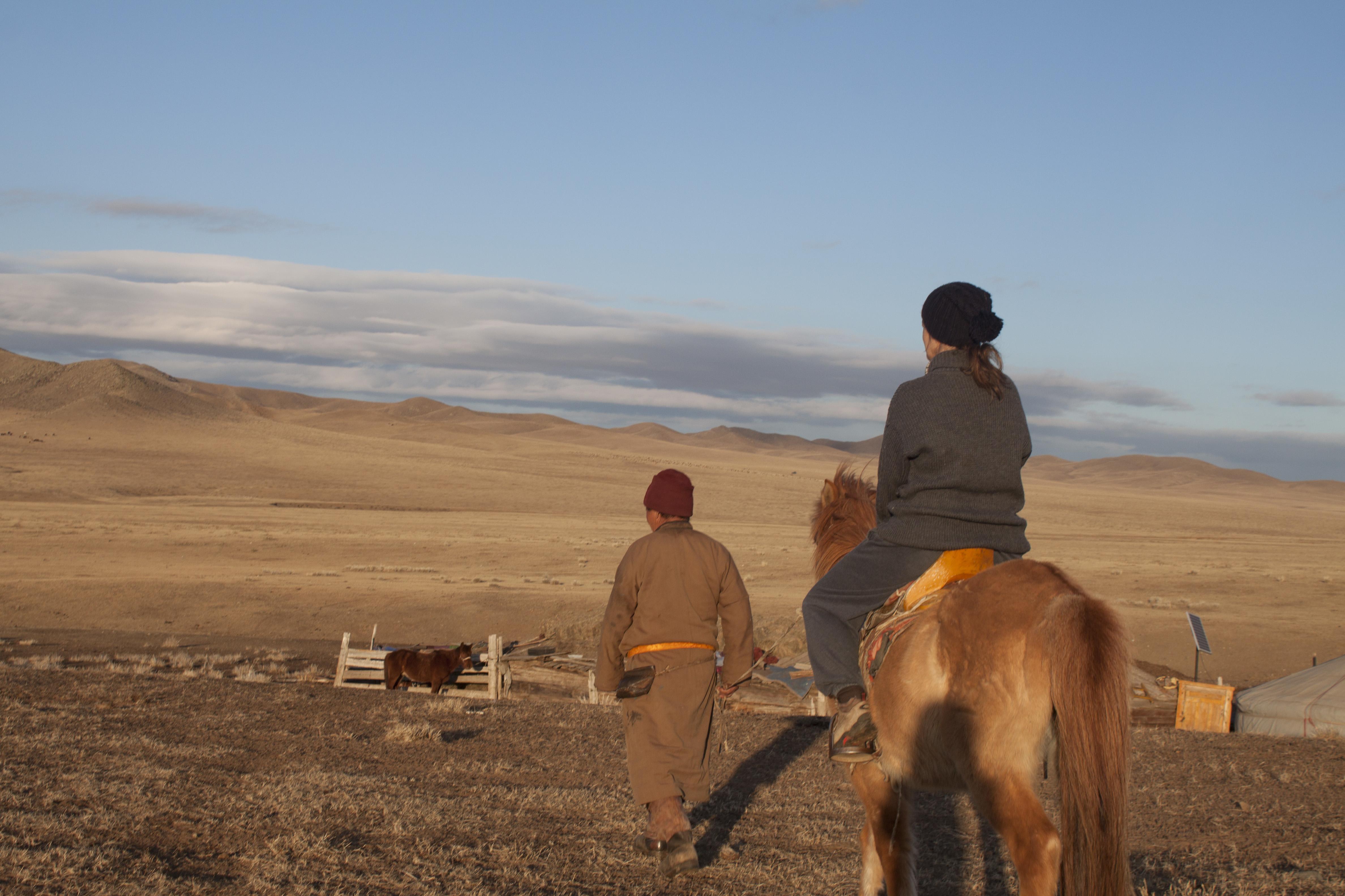 Two people from a local nomadic tribe attend to livestock on Mongolian Steppe, Asia. Nomads living on the Mongolian Steppe take care of their farm animals.