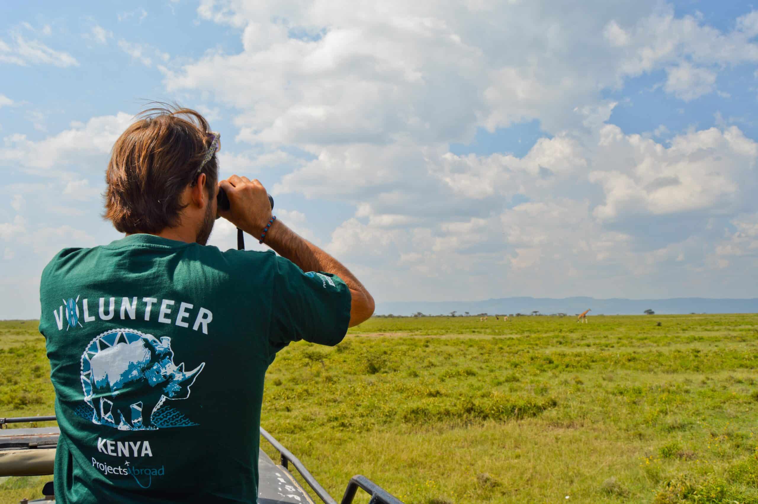 A conservation volunteer in Kenya searches for wildlife