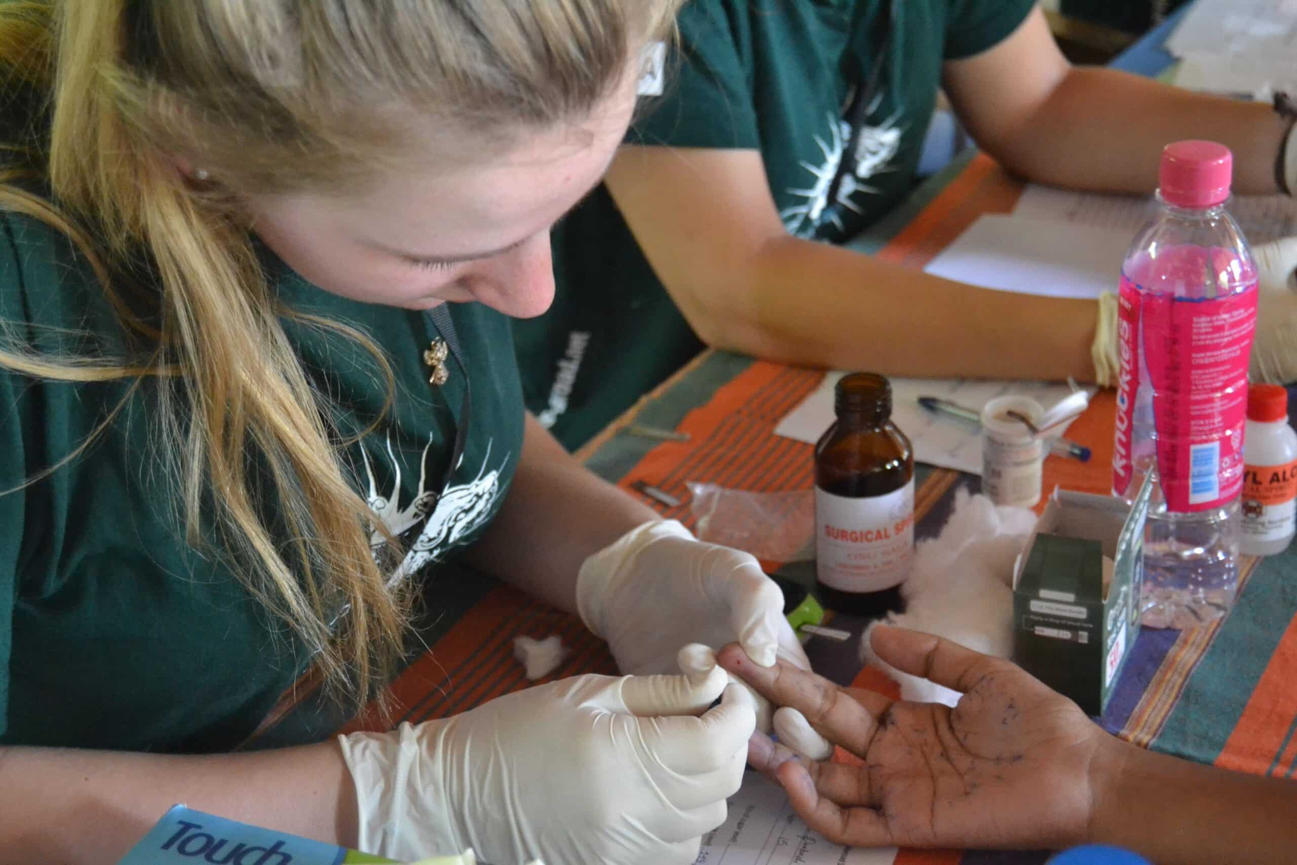 On a medical elective placement abroad, a student does a blood sugar test for a woman in Sri Lanka.