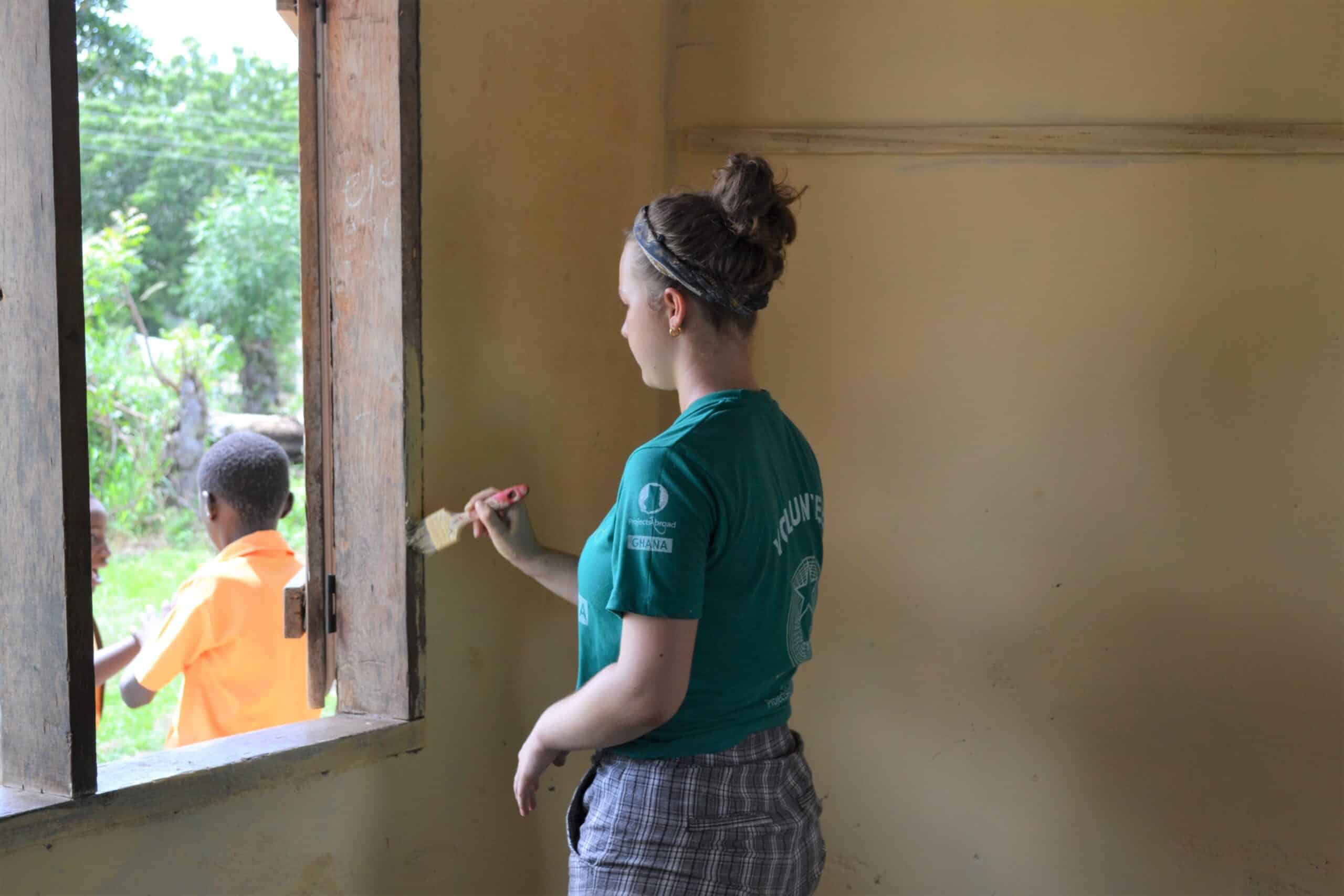 A high school student renovates a local school in Ghana during her community volunteer work for teenagers.