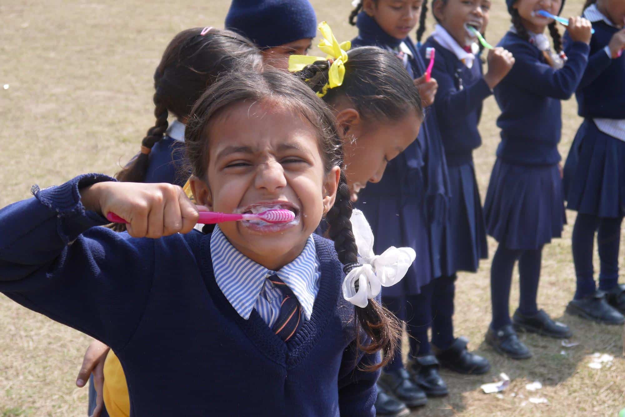 A young girl brushes her teeth during a hygiene workshop in Nepal